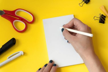 Yaratıcı bir çalışma alanı modeli ve elinde kalem var. Kırtasiye seti. Okula dönelim. Boş alanı olan üst görünüm masaüstü. Düzleştirme biçimi