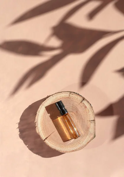 Gölgeli bir ahşap kesim üzerinde kahverengi sıvı ile cam parfüm testi. Üst görünüm