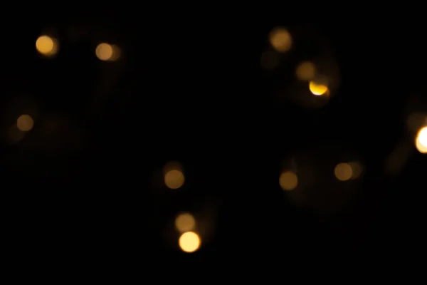 Defokussierte Bokeh-Lichter auf schwarzem Hintergrund, ein abstrakter, natürlich verschwommener Hintergrund — Stockfoto