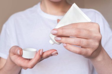 Doğal manikürlü, beyaz, boş kozmetik tüplü kadın elleri. Nemlendirici losyon. Cilt bakımı