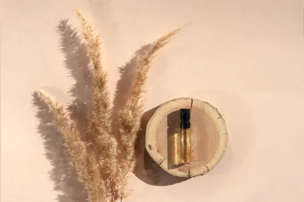 Testeur de parfum avec liquide transparent sur une gravure sur bois avec herbe pampa sur fond beige — Photo