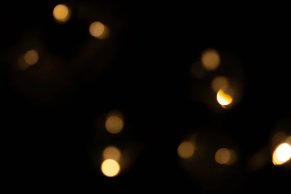 Defocused bokeh lights of a garland on black background, an abstract naturally blurred backdrop — Stock Photo, Image