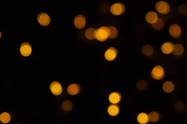 Defokussierte Bokeh-Lichter auf schwarzem Hintergrund, ein abstrakter, natürlich verschwommener Hintergrund — Stockfoto