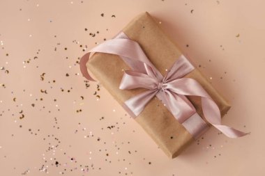 Yaş günü ya da yeni yıl hediyesi olarak kraft kağıdında yumuşak bej arka planda parlak pembe kurdele var. Xmas bileşimi