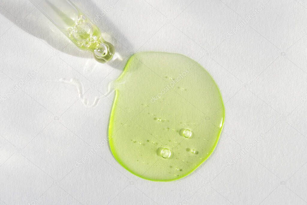 Pipette with green fluid hyaluronic acid on white background. Cosmetics and healthcare concept closeup