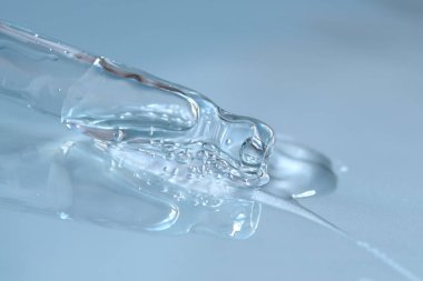 Mavi monokrom arka planında sıvı hyaluronik asit olan bir boru. Kozmetik ve sağlık konsepti yakın plan