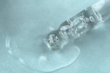 Mavi monokrom arka planında sıvı hyaluronik asit olan bir boru. Kozmetik ve sağlık konsepti yakın plan