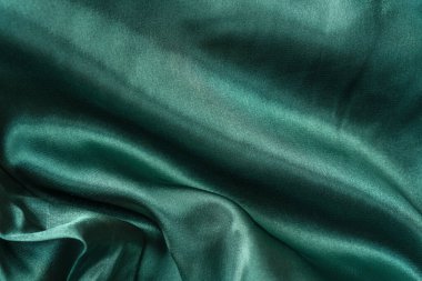 Zarif, pürüzsüz yeşil ipek ya da saten katlar. Kumaş dokusu arka planı. Soyut duvar kağıdı