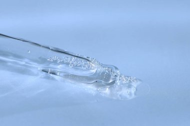 Mavi monokrom arka planında sıvı hyaluronik asit olan bir boru. Kozmetik ve sağlık konsepti yakın plan