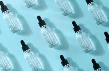 Mavi arka planda hava kabarcıkları olan şeffaf cam damlası şişesi deseni gün ışığında. 