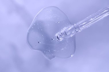 Mavi monokrom arka planında sıvı hyaluronik asit olan bir boru. Kozmetik ve sağlık konsepti yakın plan