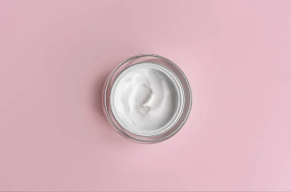 Pembe arka planda beyaz krema kavanozu. Güzellik kozmetik sunumu. Üst görünüm