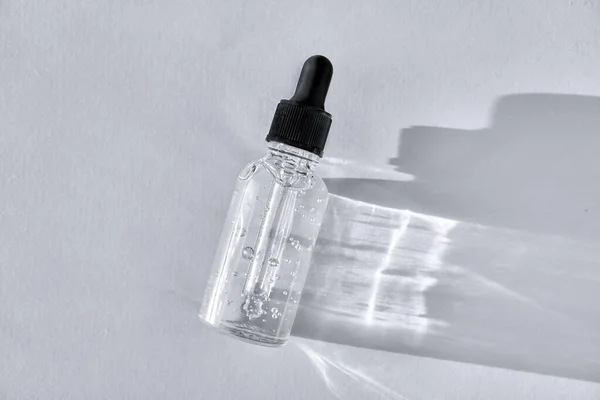 Transparante glazen druppelflesje met luchtbellen op grijze achtergrond. Pipetteer met vloeibaar hyaluronzuur — Stockfoto