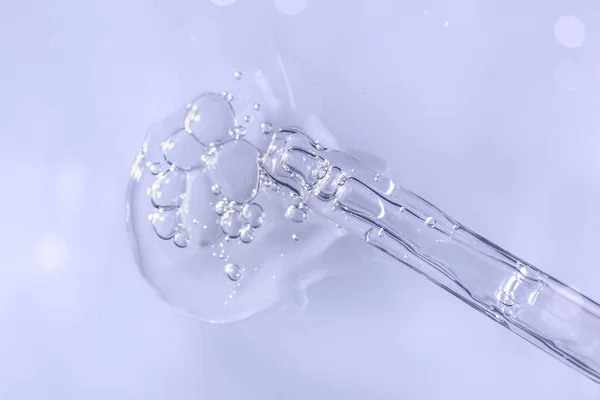 Pipette with fluid hyaluronic acid on monochrome violet background. Cosmetics and healthcare concept closeup — Foto de Stock