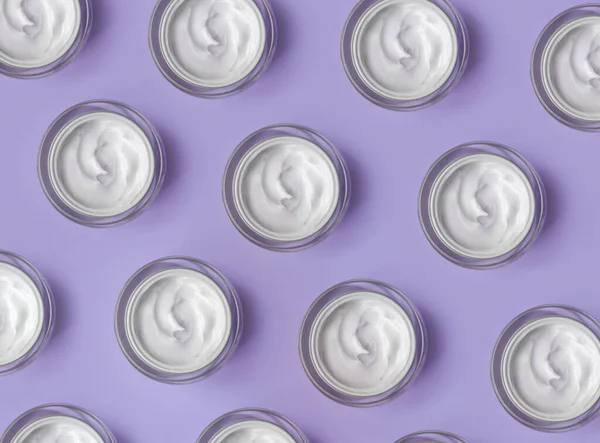 Pattern of White cream jar on violet blue background close-up. Beauty cosmetics presentation. Top view