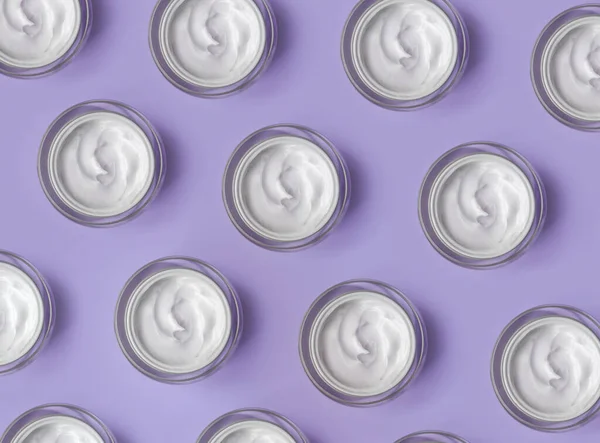 Pattern of White cream jar on violet blue background close-up. Beauty cosmetics presentation. Top view ロイヤリティフリーのストック画像