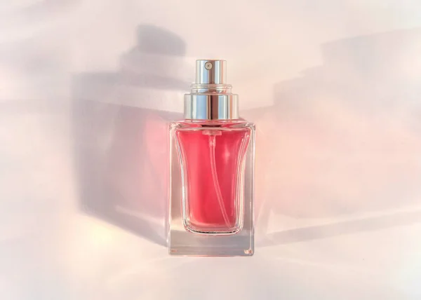 Transparent perfume bottle lying on pink background — 图库照片