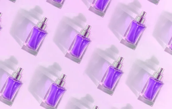 Візерунок прозорої пляшки з парфумами лежить на рожевому фіолетовому фоні — стокове фото