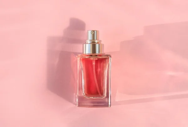 Transparent perfume bottle lying on pink background — Stockfoto