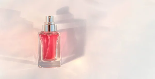 透明香水瓶のバナーピンクの背景に横たわっている — ストック写真