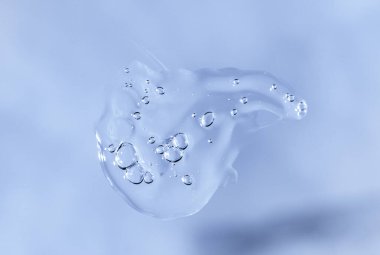 Drop of Fluid hyaluronic acid on blue monochrome background. Cosmetics and healthcare concept closeup