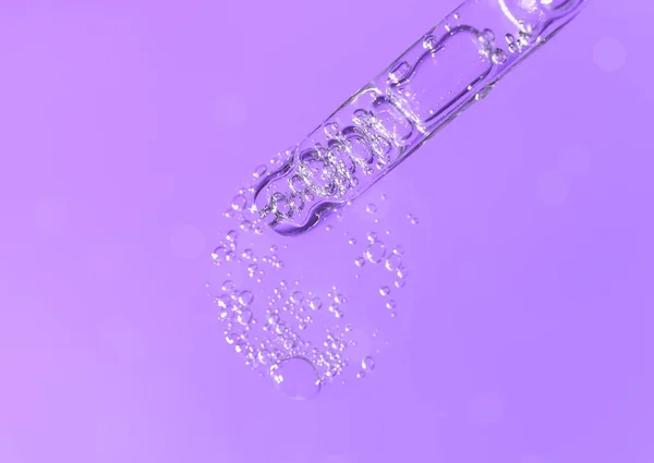 Pipette with fluid hyaluronic acid or serum on monochrome violet background. Cosmetics and healthcare concept closeup — Foto de Stock