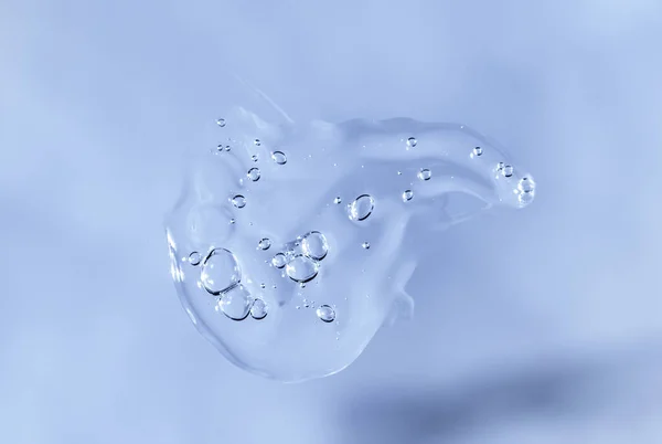 Drop of Fluid hyaluronic acid on blue monochrome background. Cosmetics and healthcare concept closeup — Foto de Stock