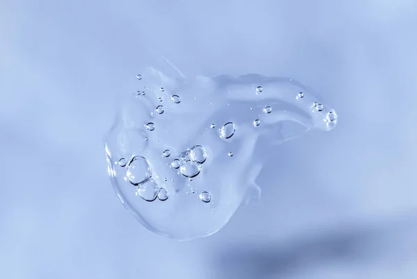 Drop of Fluid hyaluronic acid on blue monochrome background. Cosmetics and healthcare concept closeup ロイヤリティフリーのストック写真