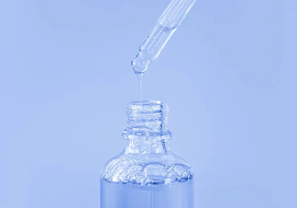 透明なヒアルロン酸または血清を青色の背景に持つピペット。化粧品とヘルスケアの概念を閉じる — ストック写真