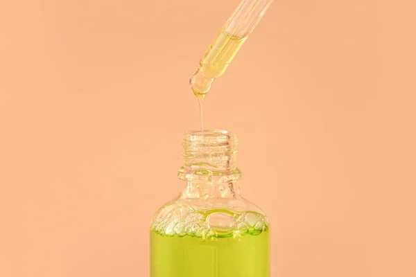 Pipett med grön vätskehyaluronsyra eller serum på beige bakgrund. Kosmetika och sjukvård koncept närbild — Stockfoto