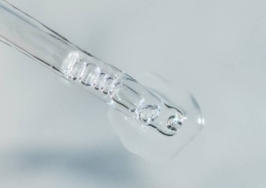 Tek renkli gri arka planda sıvı hyaluronik asit bulunan bir boru. Kozmetik ve sağlık konsepti yakın plan