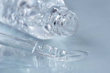 Sıvı hyaluronik asitli boru ve mavi arka planda bir şişe açtı. Kozmetik ve sağlık konsepti yakın plan