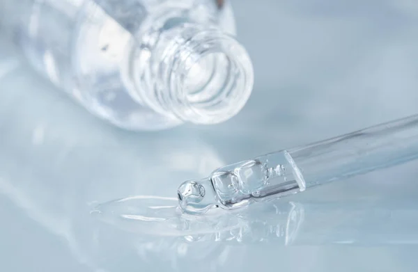 Sıvı hyaluronik asitli boru ve mavi arka planda bir şişe açtı. Kozmetik ve sağlık konsepti yakın plan