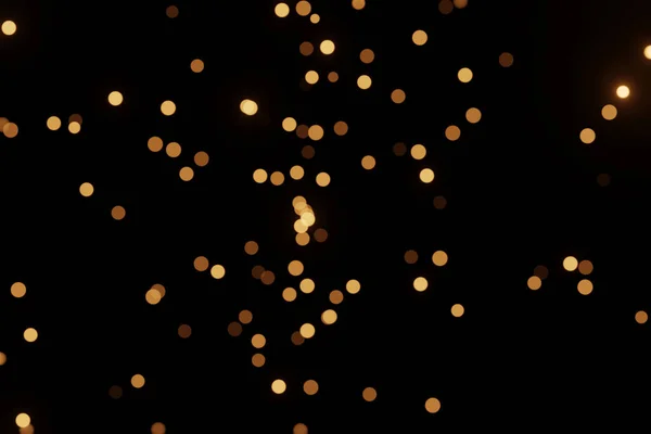 Luzes de bokeh desfocadas no fundo preto, um cenário abstrato naturalmente desfocado — Fotografia de Stock