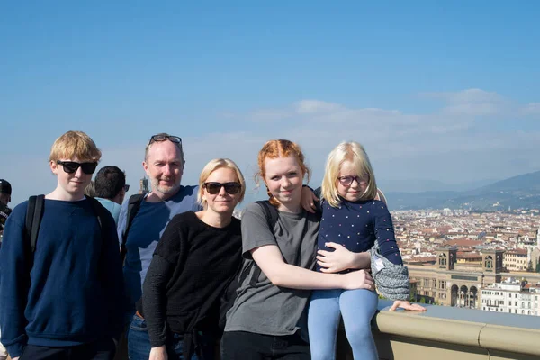 Parents and three kids stood together with a view of Florence in the Background