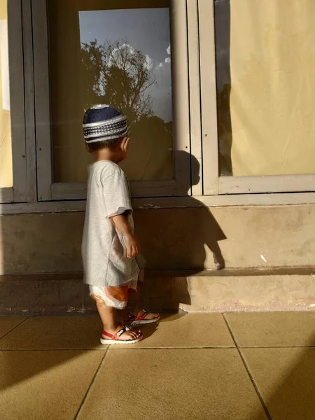 Elinde bir torba su olan çocuk, şemsiye penceresinden dışarı bakıyor, yansıması olan.
