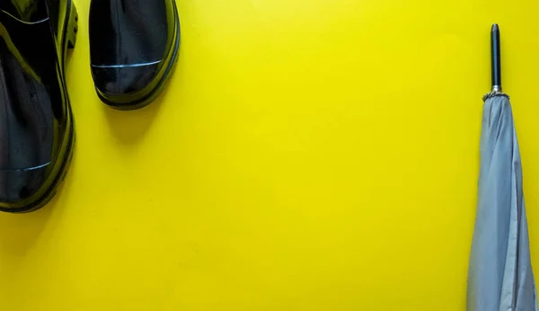 rain boots and umbrella on yellow background