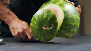 Güzel yeşil karpuz. Bir adam karpuzu bıçakla ikiye böler.