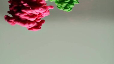 Suyun altında dönen kırmızı ve yeşil mürekkep. Soyut duman patlaması etkisi. Soyut gri arkaplan