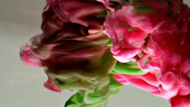 Suyun altında dönen kırmızı ve yeşil mürekkep. Soyut duman patlaması etkisi. Soyut gri arkaplan