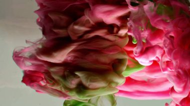 Suyun altında dönen kırmızı ve yeşil mürekkep. Soyut duman patlaması etkisi. Soyut gri arkaplan