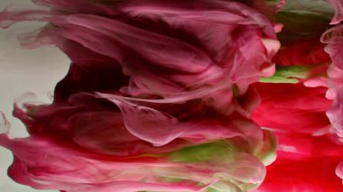 Suyun altında dönen kırmızı ve yeşil mürekkep. Soyut duman patlaması etkisi. Soyut gri arkaplan