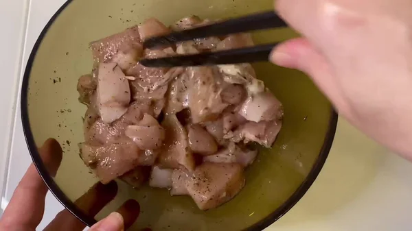 Poultry meat dish in a transparent bowl transverse with black pepper and paprika for frying on fire