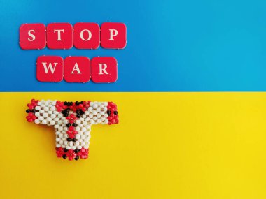 Kelimeler Ukrayna bayrağı ve boncuk işleme arkaplanındaki kişisel harflerle savaşı durdurun.