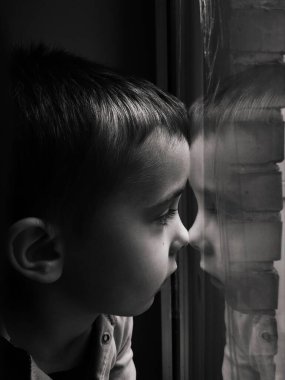 Ukrayna 'daki savaş sırasında patlama dalgasından korunmak için camdan koli bandıyla kapatılmış küçük bir çocuğun siyah beyaz portresi.