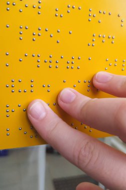 Kız açık havada sarı körler alfabesi işareti okuyor. Körler alfabesi okuyan bir kadının yakın çekimi. Körler ve sakatlar günü kavramı. Körlük