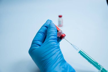 Elinde şırınga olan mavi eldiveni ver. Elinde keskin bir iğne olan şırınga. Tıbbi tedavi konsepti. Laboratuvarın arka grubu. Sağlık sigortası konsepti. Aşılama kavramı.