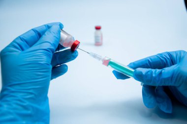 Elinde şırınga olan mavi eldiveni ver. Elinde keskin bir iğne olan şırınga. Tıbbi tedavi konsepti. Laboratuvarın arka grubu. Sağlık sigortası konsepti. Aşılama kavramı.