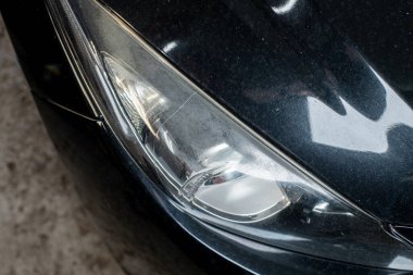 Gri arka planda siyah modern arabanın ksenon ışığıyla yakın plan ön far. 