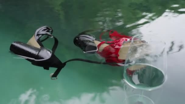 Black womens shoes, a glass of wine and red underwear are floating in the pool after a stormy party. Consequences of a fun birthday celebration or any other holiday. Things are floating in the pond. — Stock Video